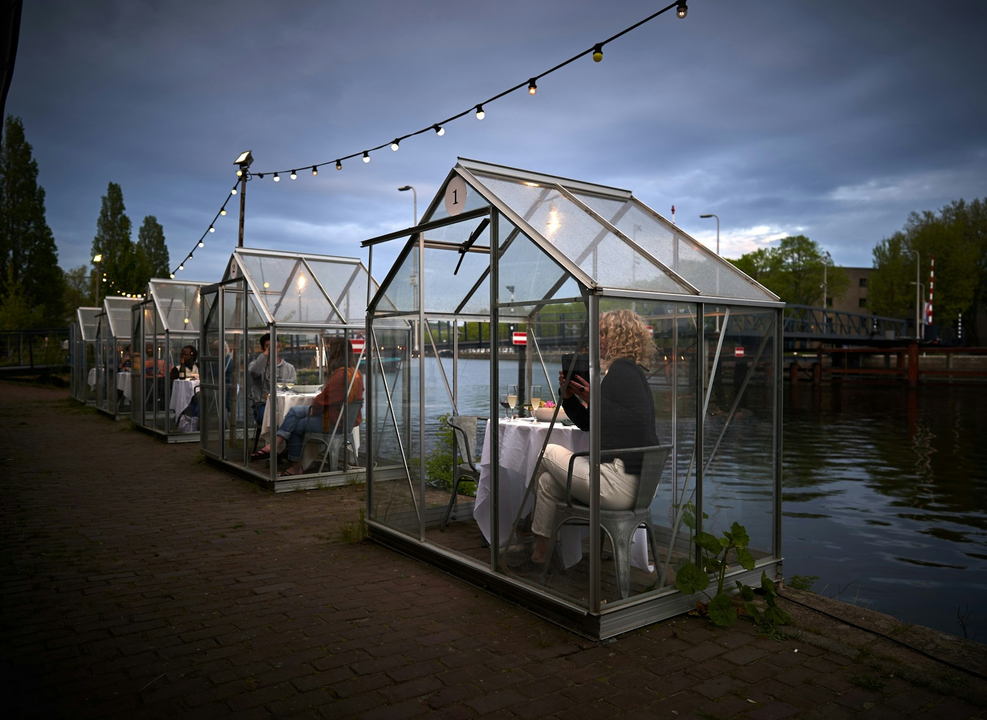Diners inside glass greenhouses that are used for social distancing